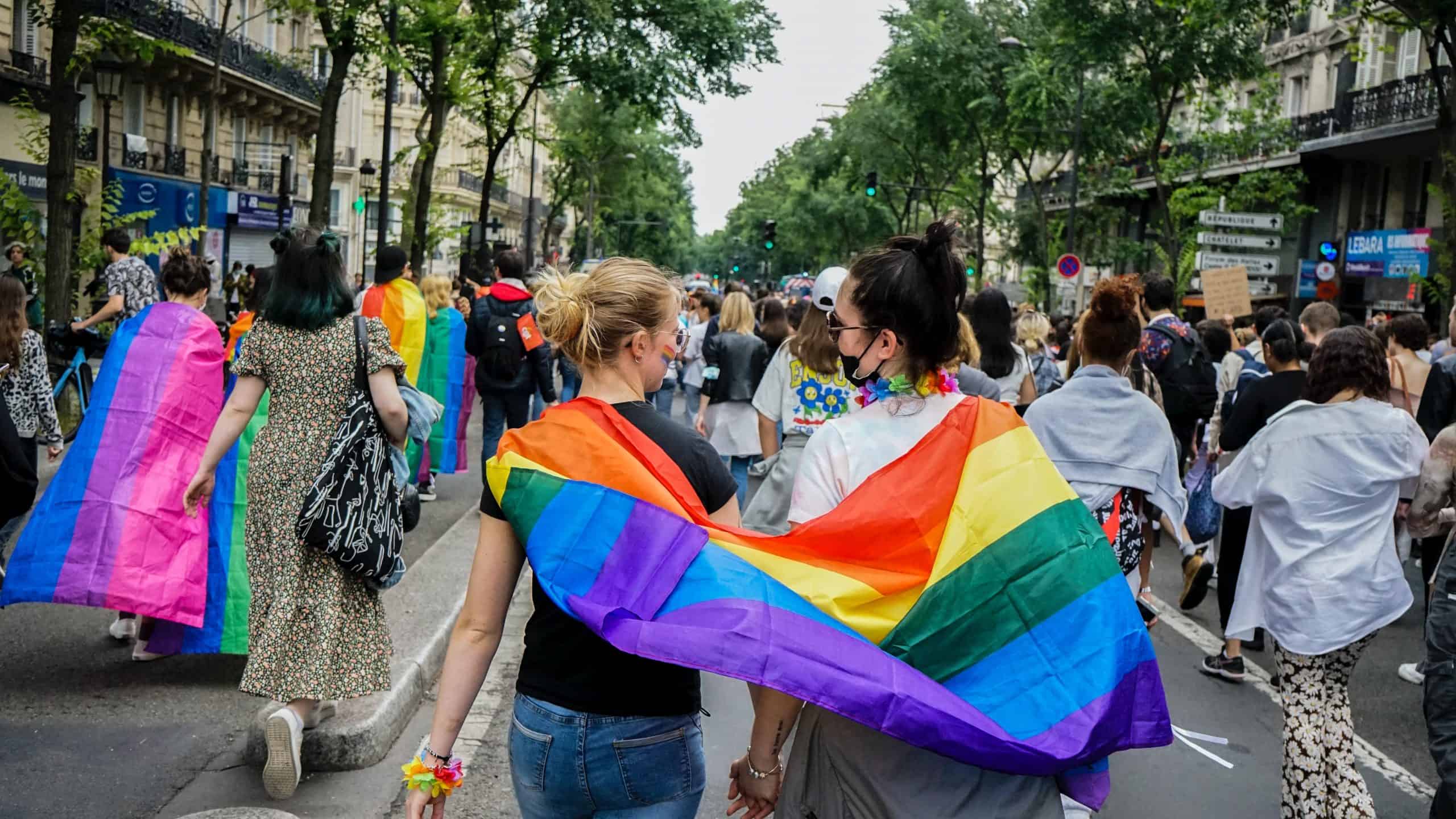 Lesbian couple walking with a rainbow flag.