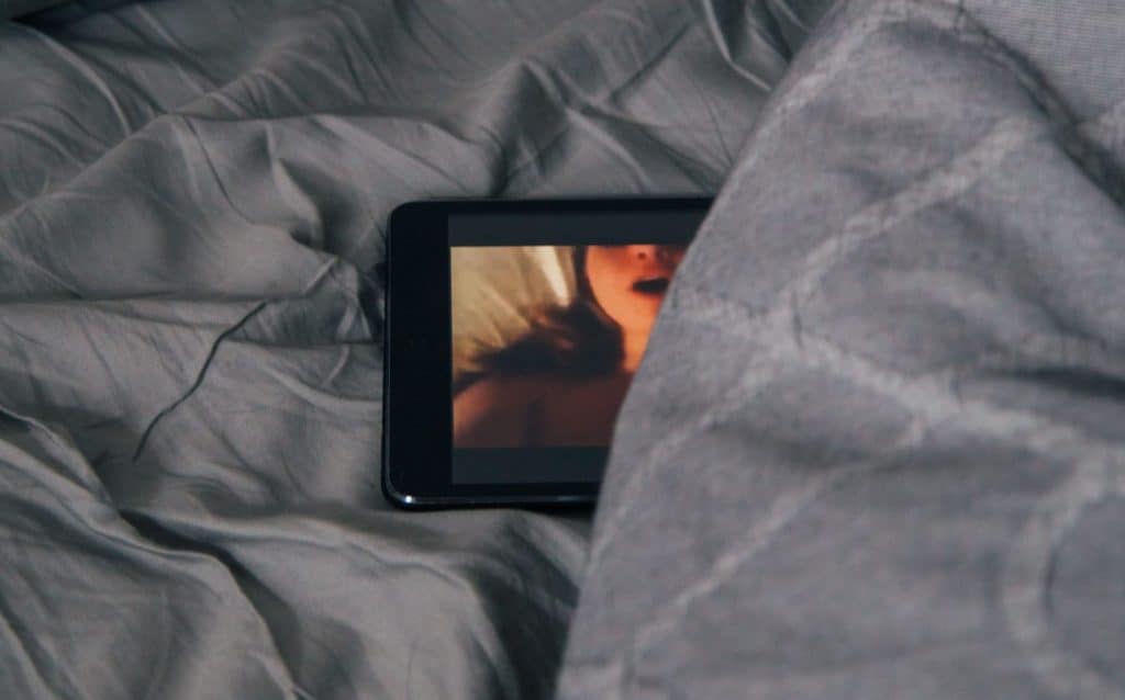 Sexual materials on phone in bed.