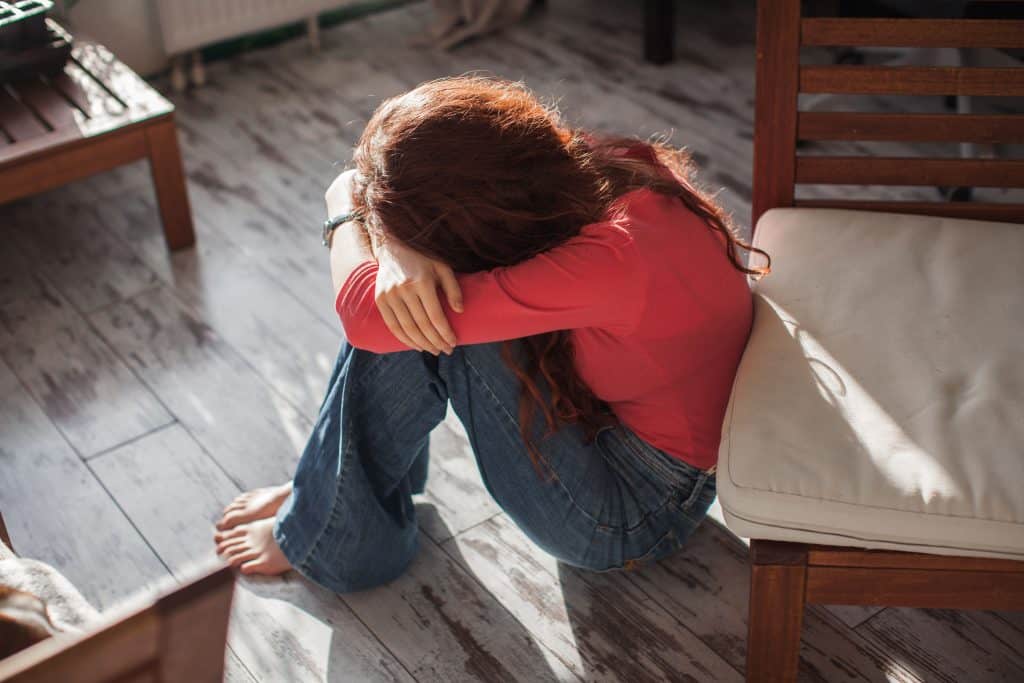 Woman sitting on the ground crying.